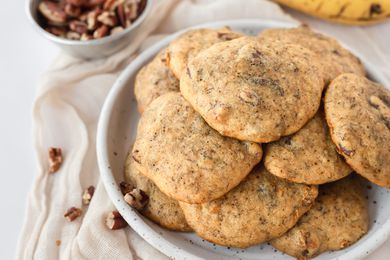 Side view of banana cookies on a white plate with a white linen underneath it.