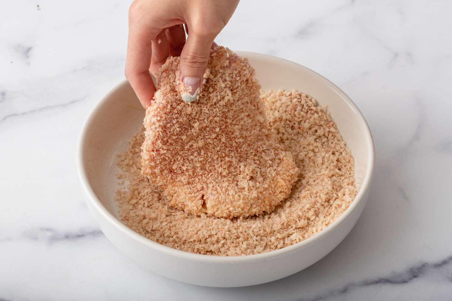 Coating pork cutlet in bread crumbs.