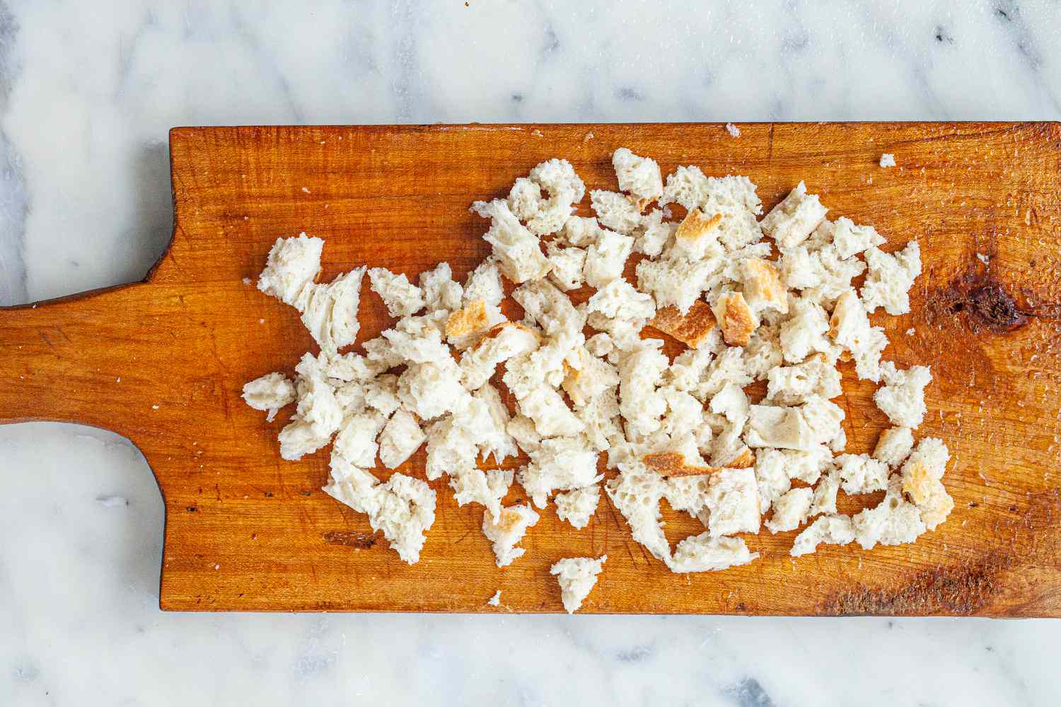 Cubed bread on a cutting board to make Spanish Style Migas.