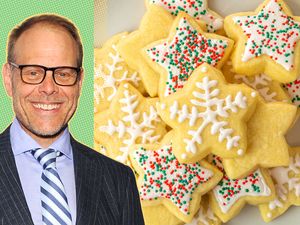 Alton Brown next to decorated sugar cookies shaped like stars with frosting and sprinkles