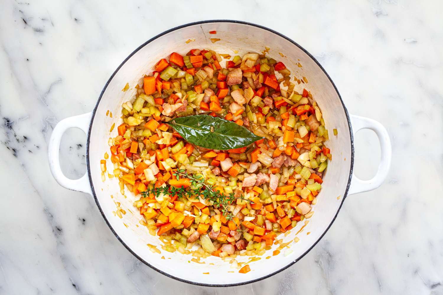 Add bay leaf, garlic, and thyme to carrots, onions, and celery for classical tomato sauce