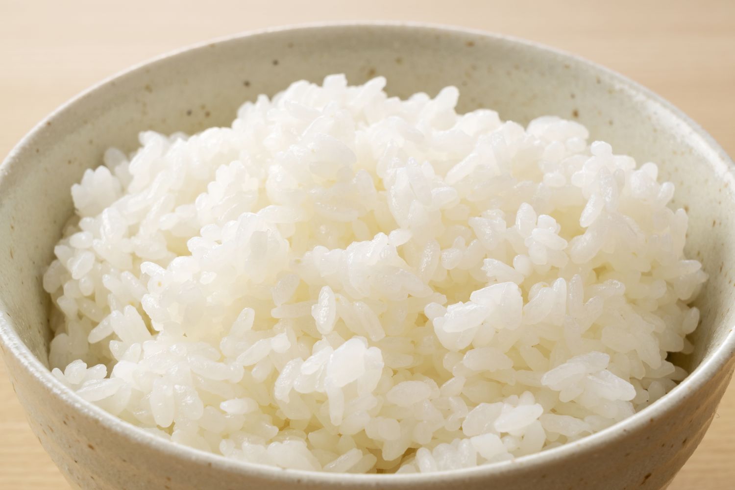 A bowl filled with cooked white rice placed on a lightcolored surface