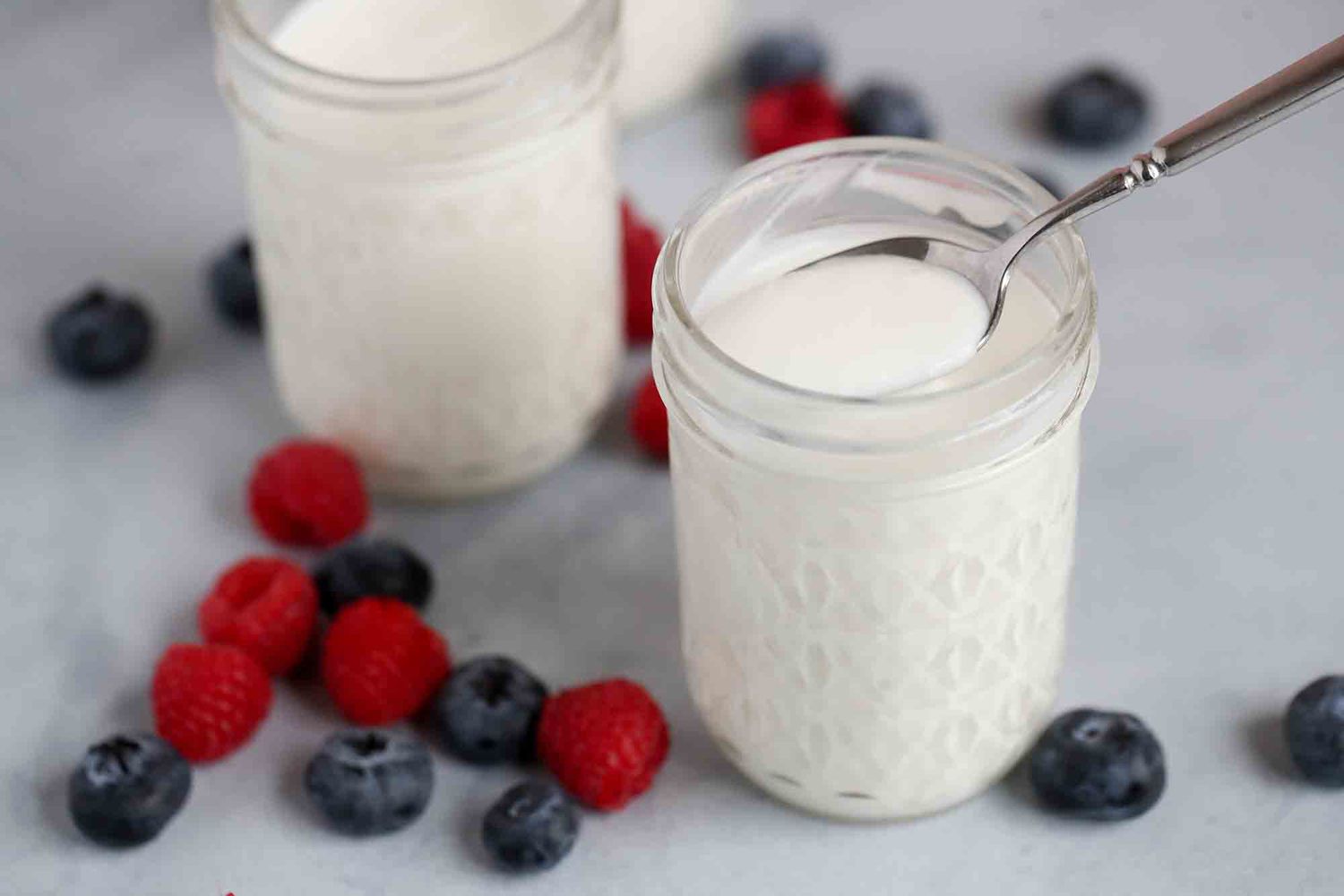 Two jars of Pressure Cooker Yogurt with berries around their bases 