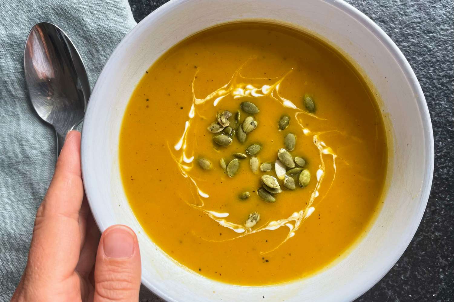 Hand holding Ina Garten's Butternut Squash Soup recipe in a bowl