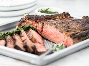 A cowboy ribeye steak sliced on a baking sheet