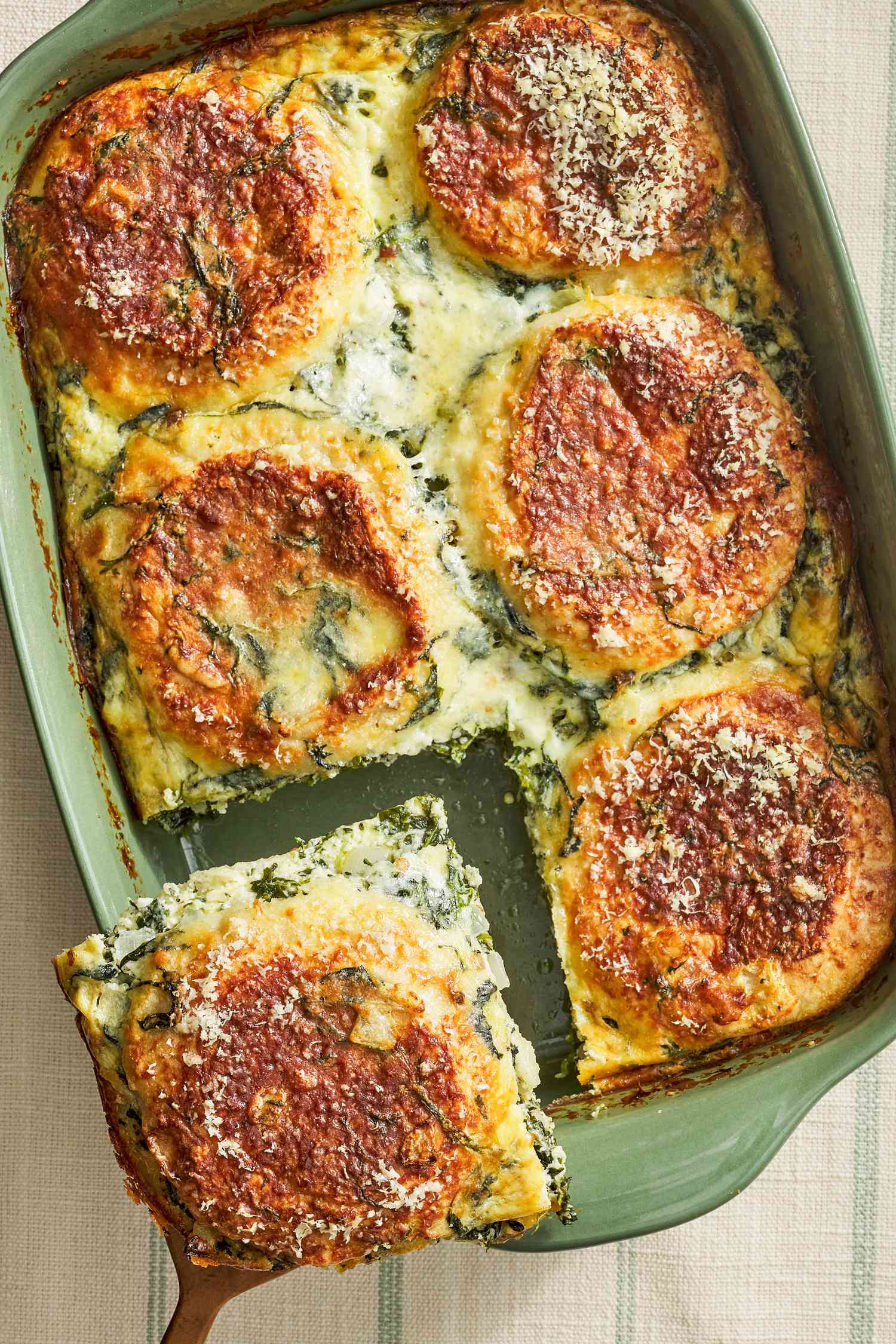 Serving of spinach florentine breakfast casserole lifted from a casserole dish