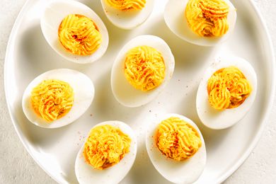 Deviled eggs arranged on a white plate, topped with a sprinkle of seasoning.