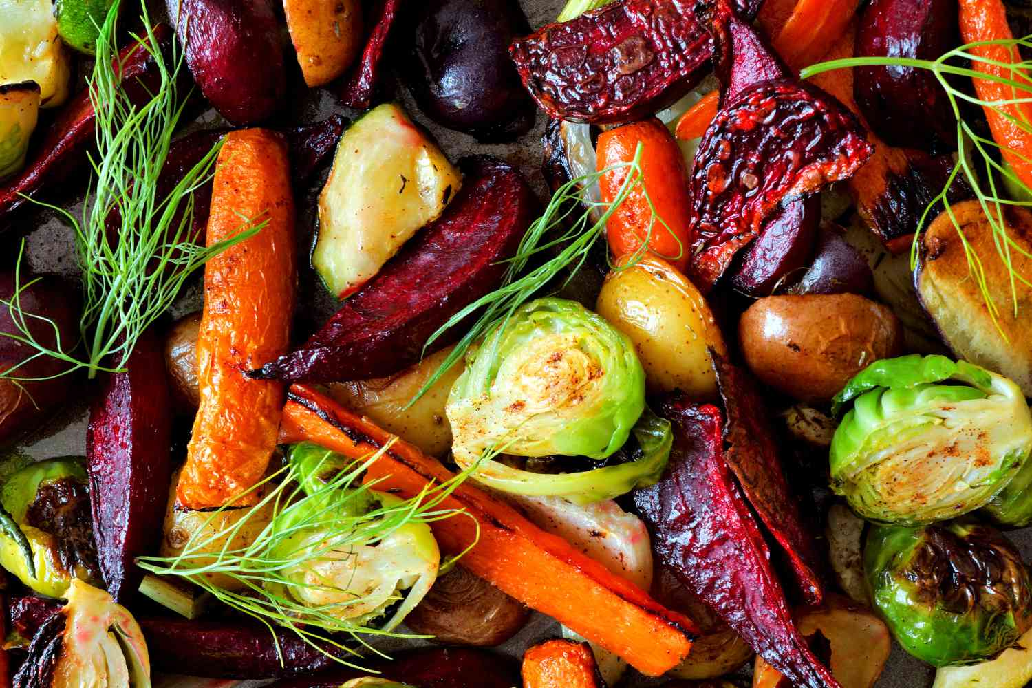 A pan of roasted vegetables, including beets, carrots, Brussels sprouts, and baby potatoes