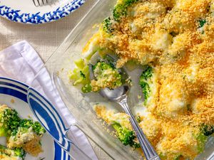 My Mom’s Famous Broccoli Cheese Casserole in a dish, one serving scooped out and added to a plate