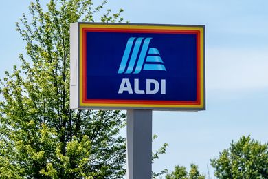 An Aldi store sign in an outdoor setting with trees visible in the background