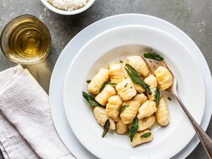 Homemade Potato Gnocchi with sage and brown butter sauce in a plate at a table