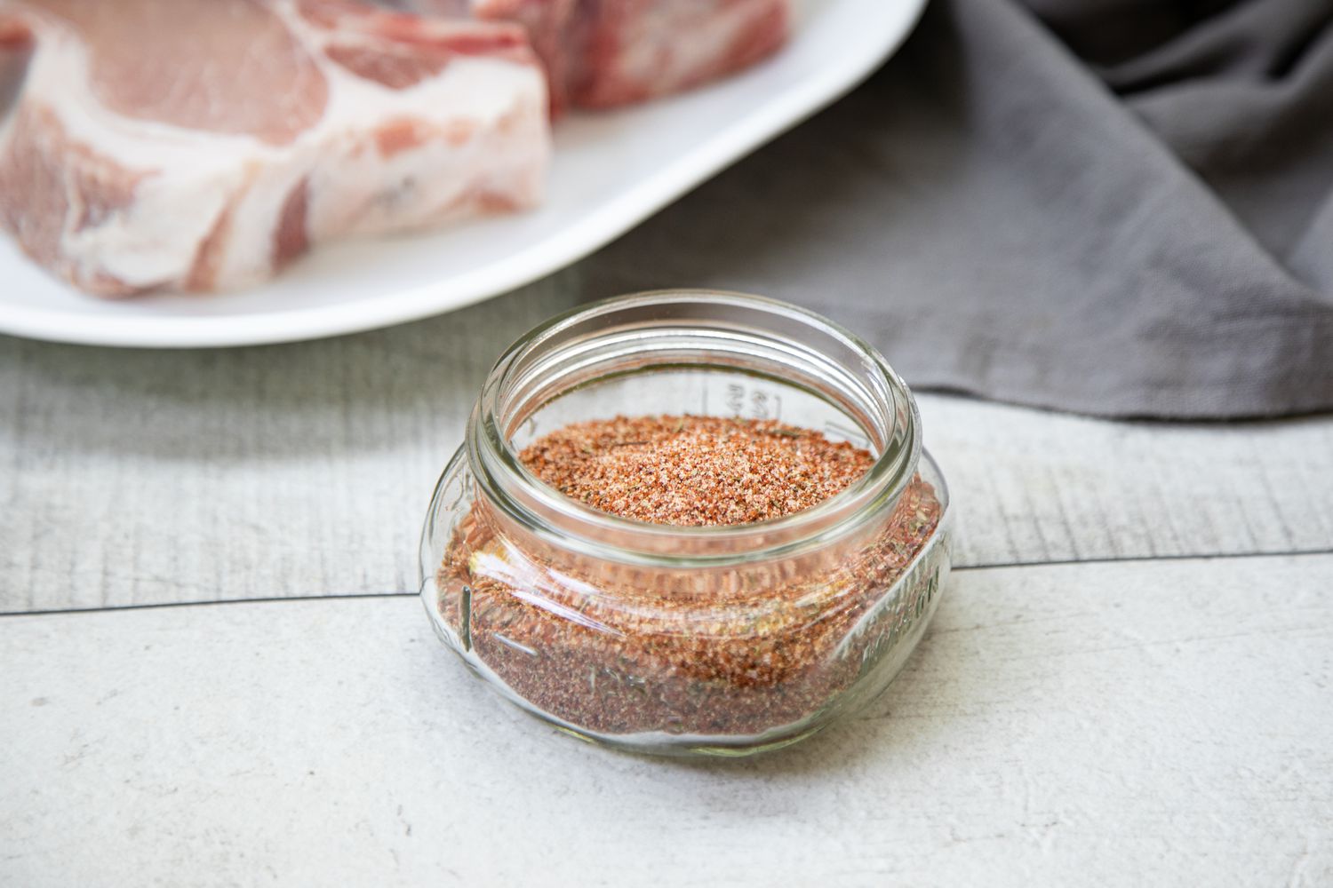 Jar of Pork Chop Seasoning with Pork Chops in Background