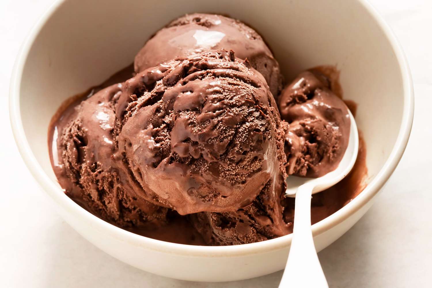 Scoops of chocolate ice cream in a bowl with a spoon