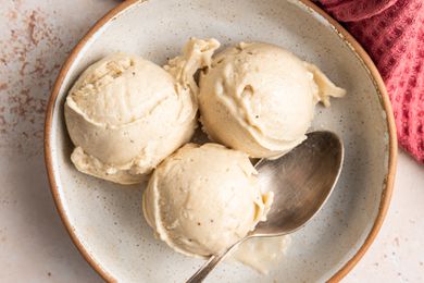 Three Scoops of Banana Nice Cream in a Bowl With a Spoon, and on the Counter, a Kitchen Towel
