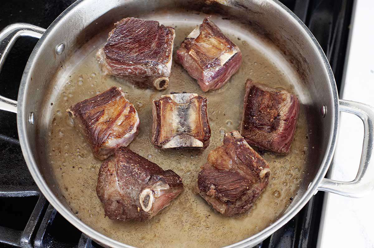 Cooking a short ribs recipe in a pan on the stove.