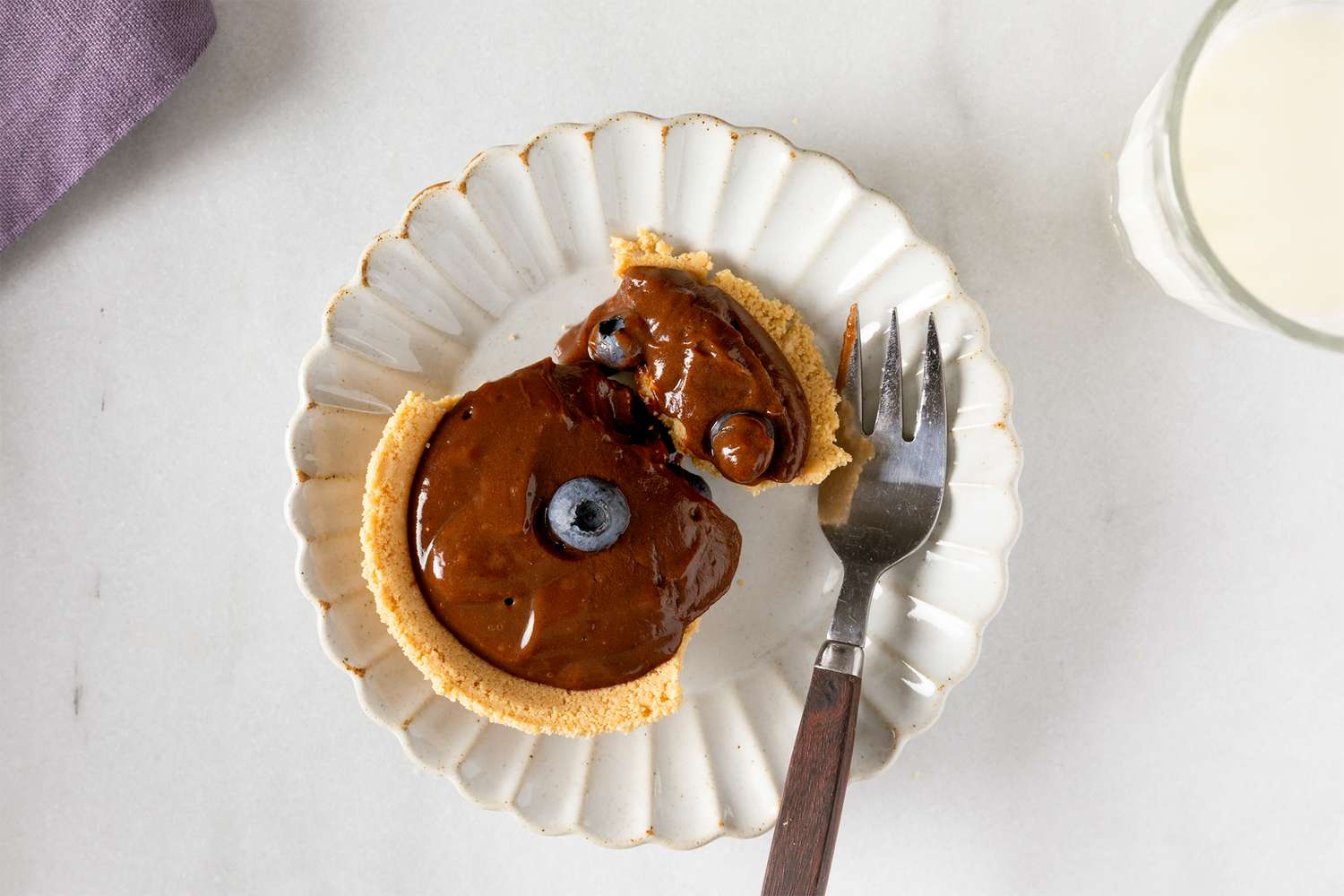 Mini chocolate pudding pie on a white plate with a fork topped with blueberries