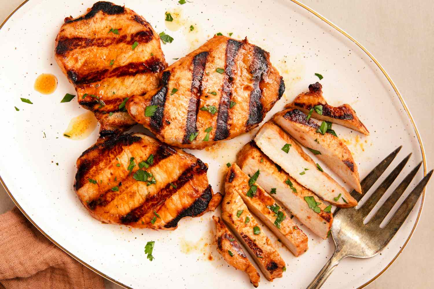 Grilled pork chops served on a plate with garnish and a fork