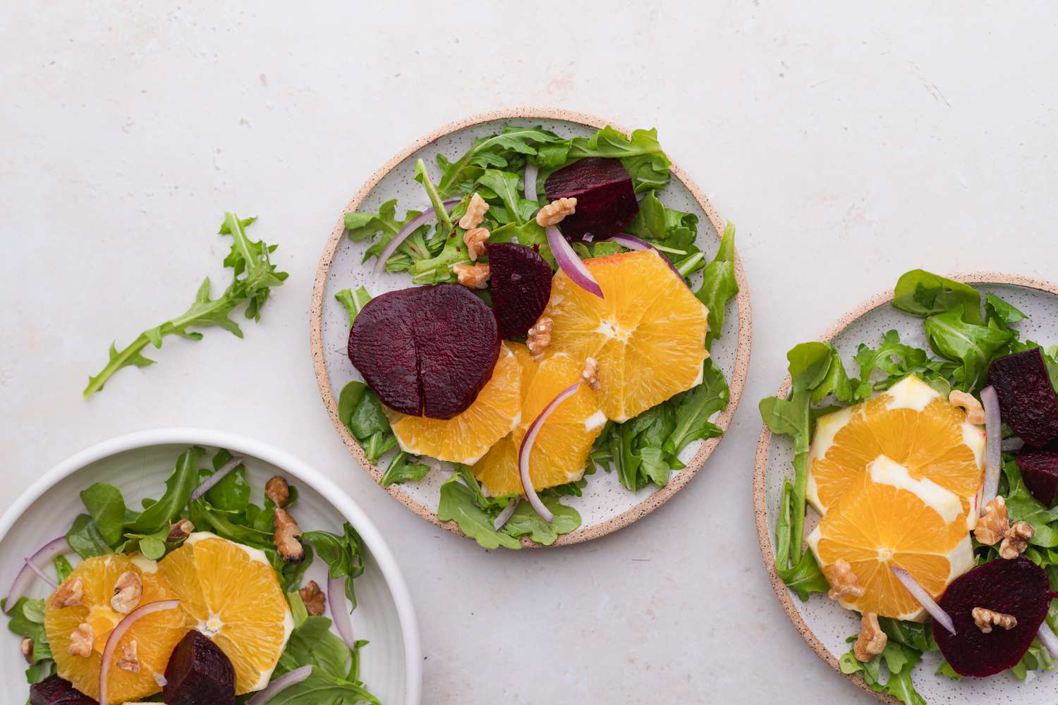 Three plates with a sliced beet and orange salad.