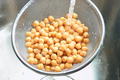 Chickpeas in a colander under running water