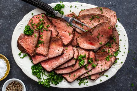 Overhead view of a platter of sliced pan fried steak.