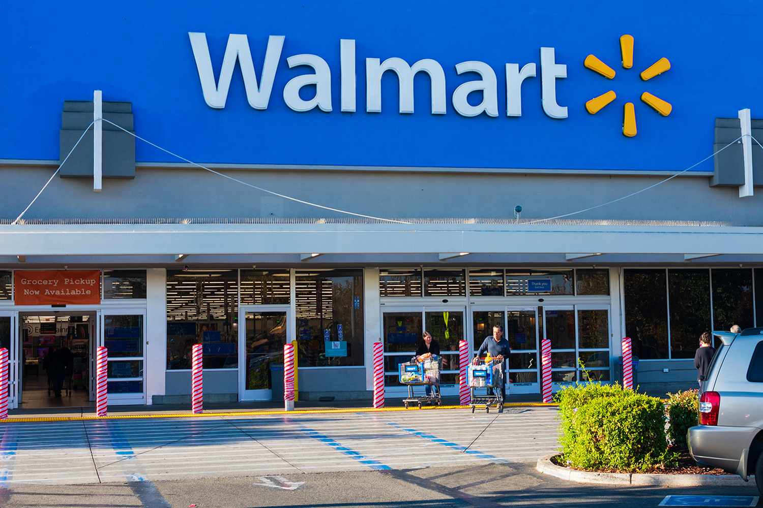 Exterior of a Walmart store with shoppers entering and exiting through sliding doors