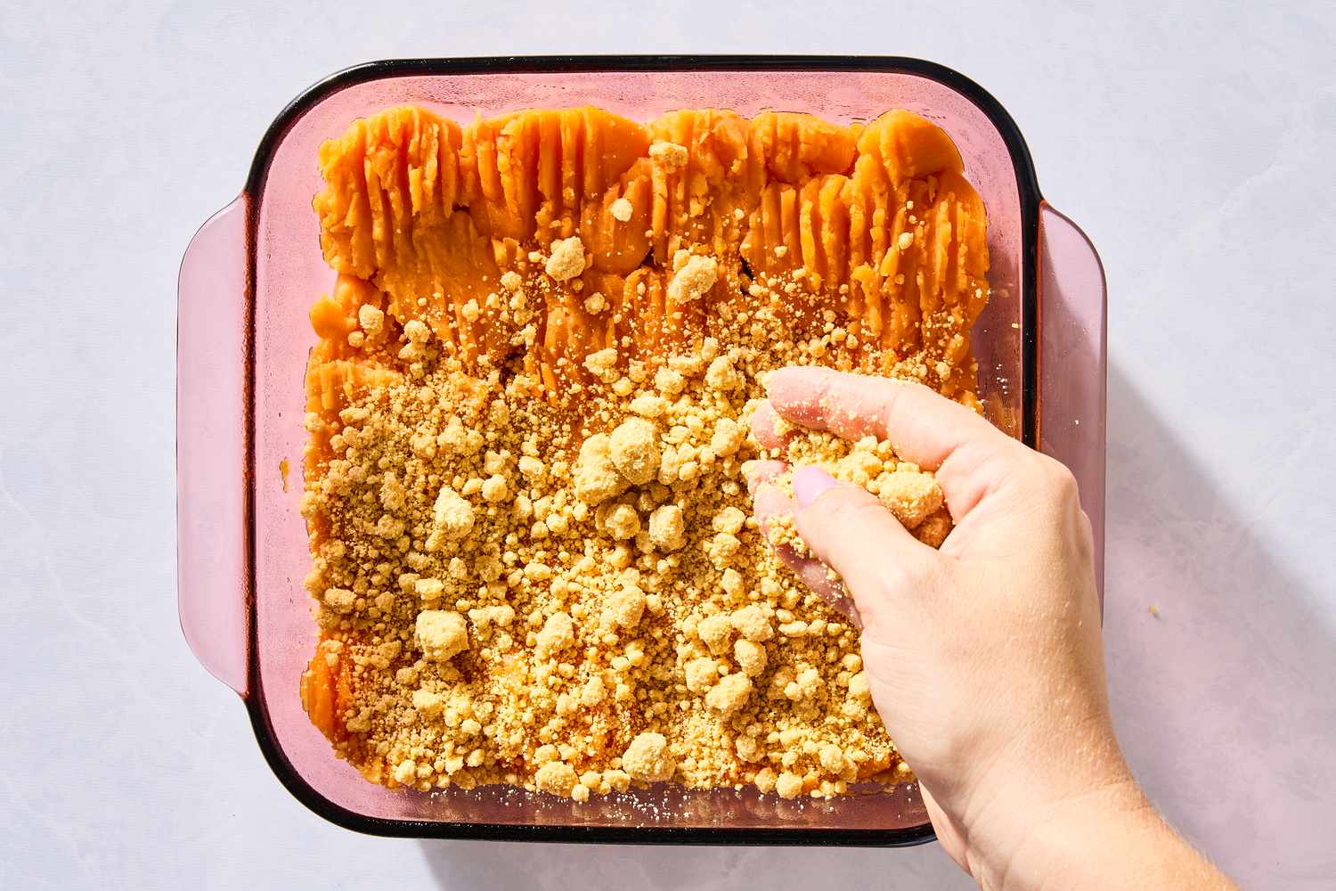 hand topping yams with cake mixture for 4-Ingredient Sweet Potato Dump Cake