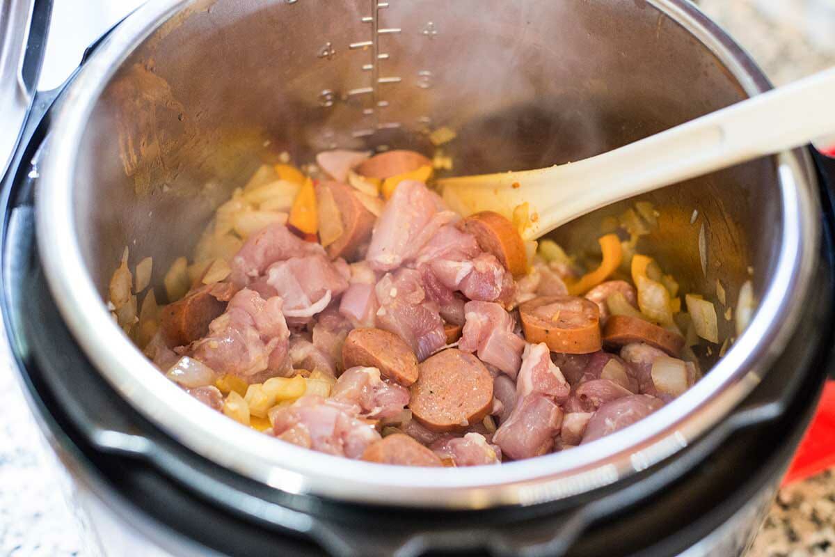Cook the vegetables and stir in the chicken and sausage for the instant pot paella