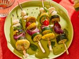 Vegetable skewers with zucchini, yellow squash, tomatoes, and mozzarella on a green plate