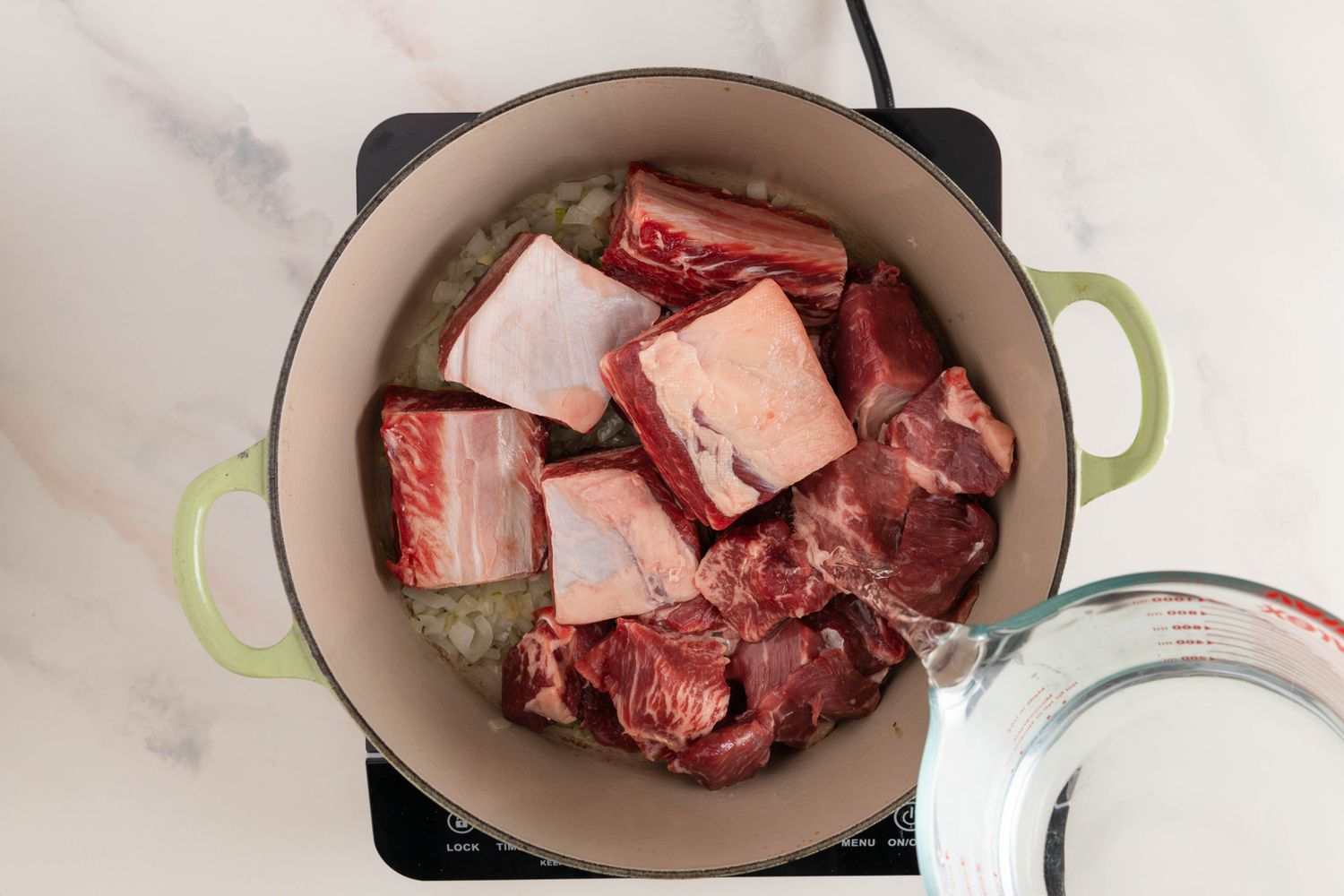 Water poured onto the beef and the aromatics in the Dutch oven (still on the induction stove) for nilagang baka recipe