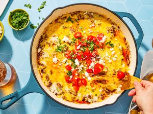 overhead view of Queso Fundido in a skillet, hand pulling dipped chip from it