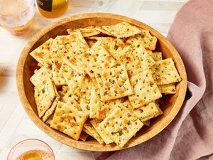 Bowl of Alabama fire crackers surrounded by a bottle and glasses of beer and a light maroon table napkin