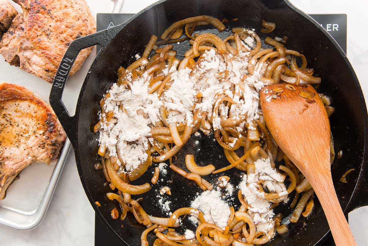 Onions and flour sauteed in a cast iron skillet with a wooden spoon.