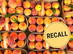 Several baskets of peaches with a recall label prominently displayed