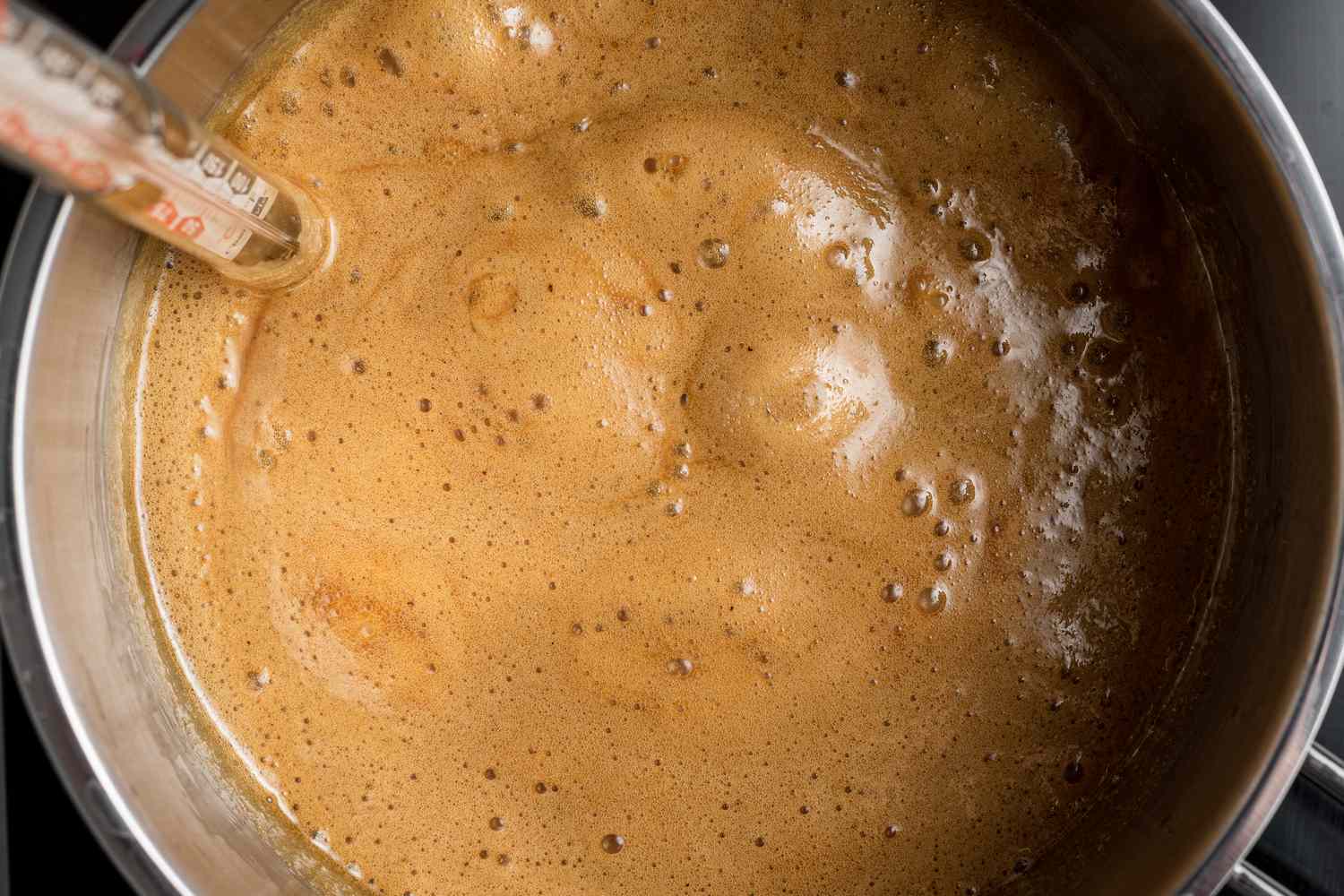 Simmering candy mixture to make a pecan praline recipe.
