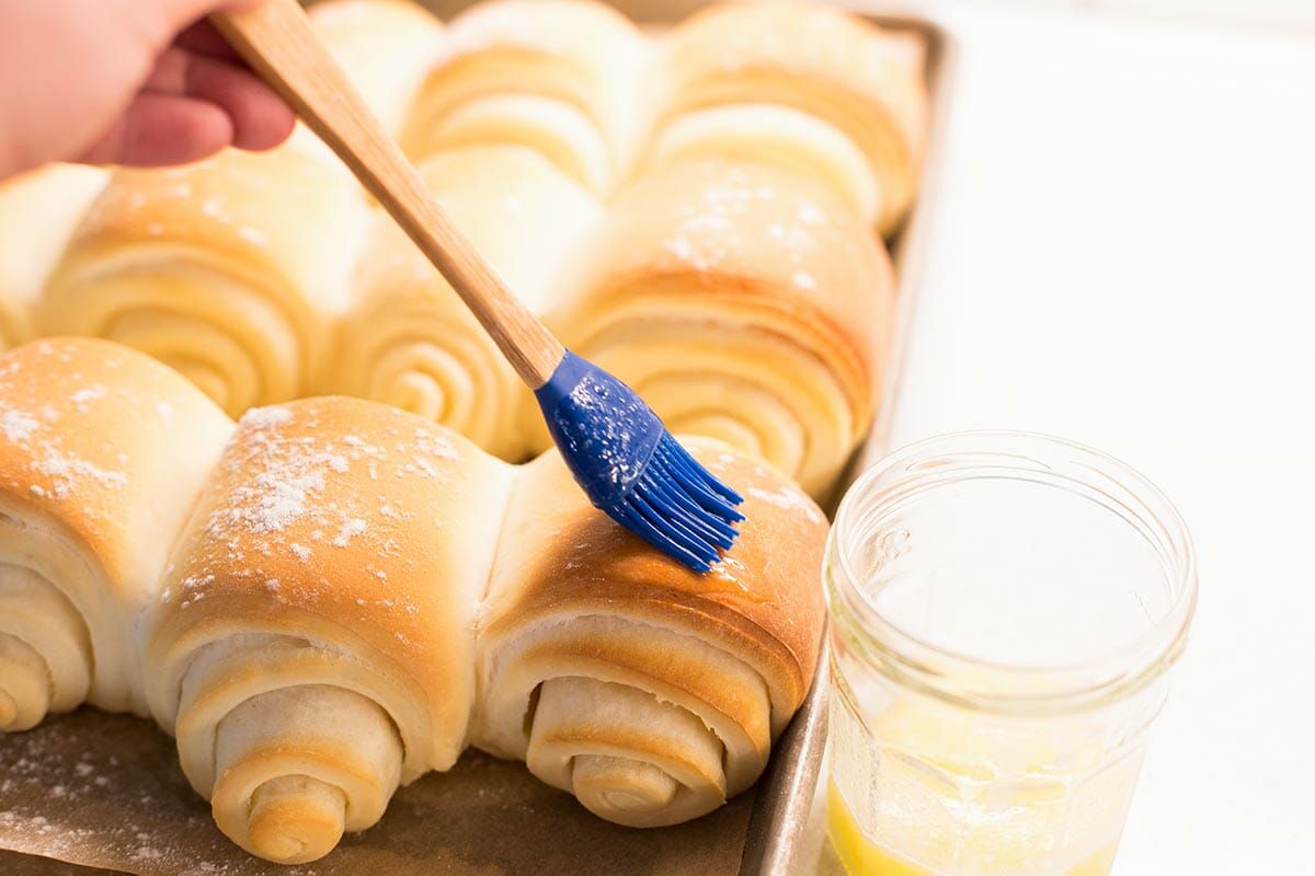 Lion house dinner roll being brushed with melted butter.