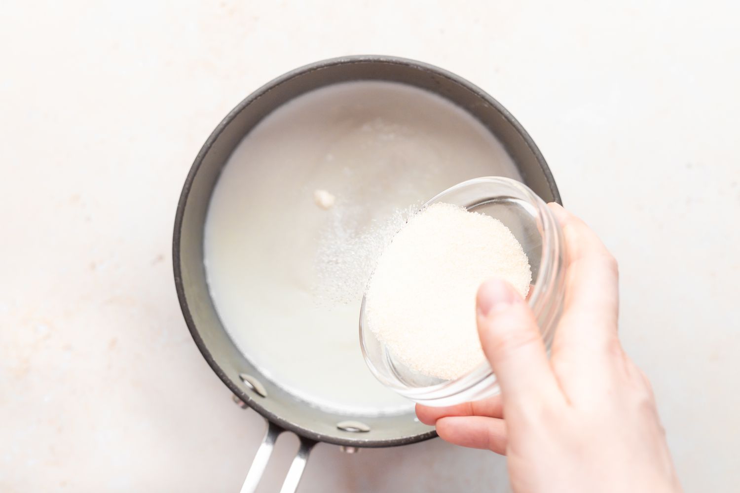 Adding ingredients to a pot to make a tapioca pudding recipe.