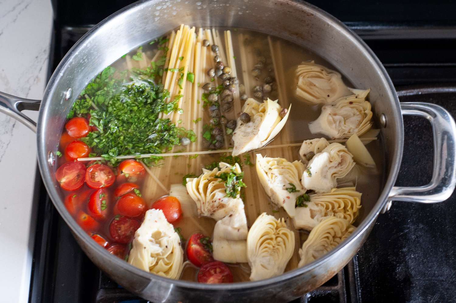 Pot of Chicken Stock with Spaghetti, Tomatoes, Artichokes, Capers, and Parsley