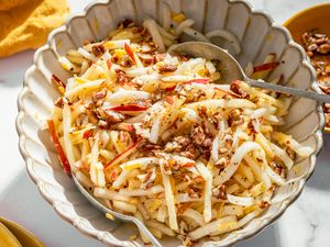 Kohlrabi and apple salad garnished with chopped nuts in a serving dish with a spoon