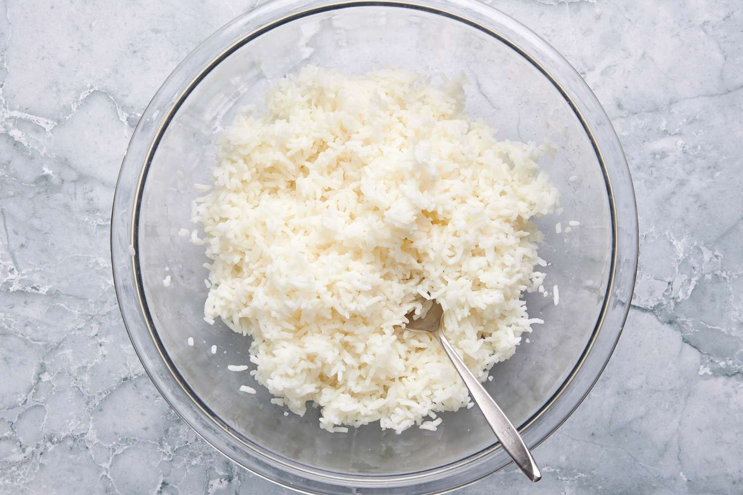 Bowl of salt-seasoned rice with a spoon for Filipino Garlic Fried Rice (Sinangag na Kanin) recipe