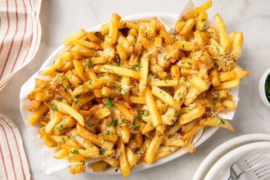 Basket of fries covered with cheese and gravy on a table