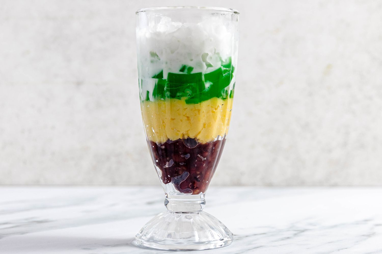 Glass of Che Ba Mau (Layers From Bottom to Top: Reed Bean Paste, Mung Beans, Pandan Jelly, Crushed Ice, and Coconut Sauce)