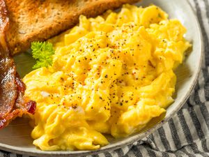 Scrambled eggs on a plate with bacon and toast