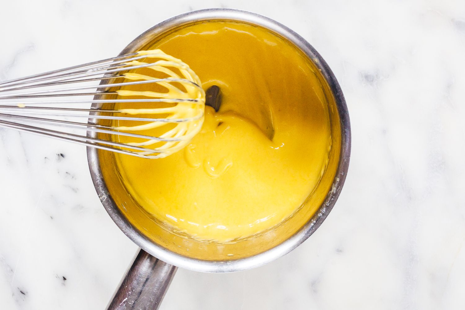 Whisking sauce to show How to Make Hollandaise for Eggs Benedict.