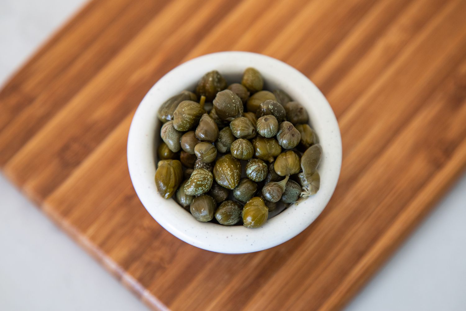Small Bowl of Capers on a Wooden Board
