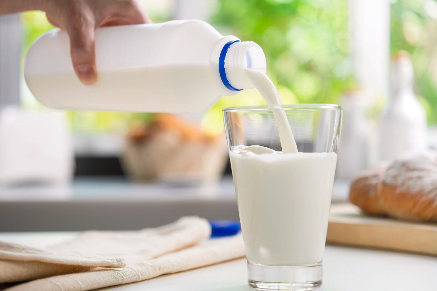 Pouring milk into a glass on a kitchen counter