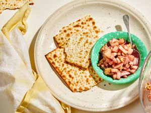 Charoset in a small turquoise dish with a spoon and broken pieces of matzo on the side