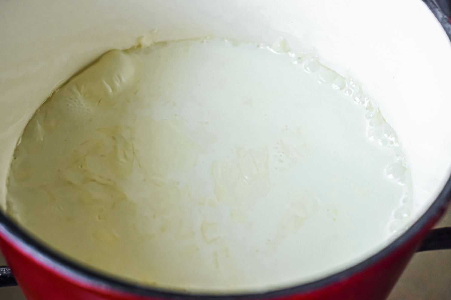 A dutch oven warming milk to show how to make fondue.
