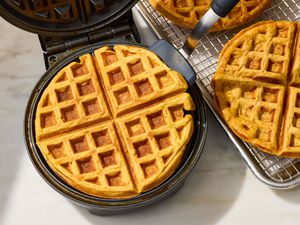 Carrot Cake Waffles in a waffle iron, some on a cooling rack