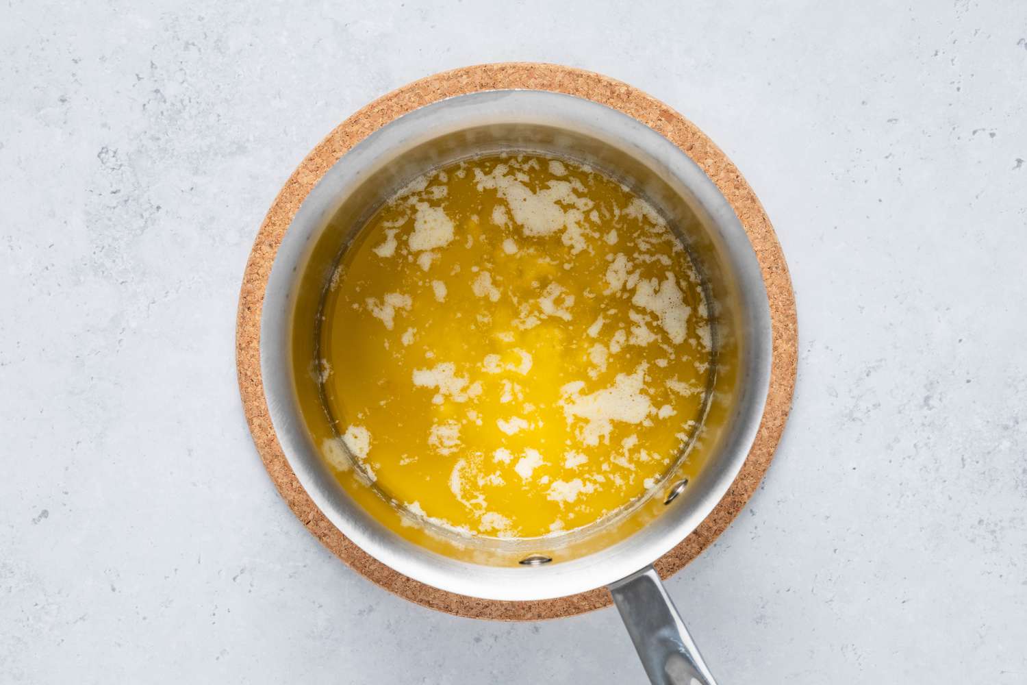 Pot of melted butter on a coaster for homemade Cosmic Brownie recipe