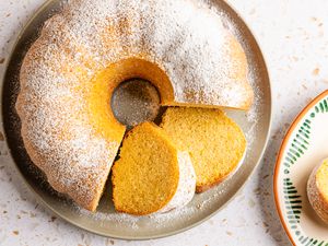 ciambellone on a platter with some of it cut into slices, and next to the platter, a slice on a plate 